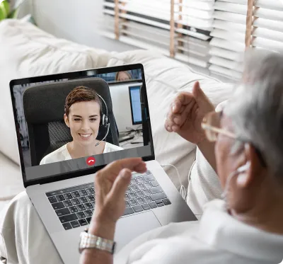 Un anziano in videoconferenza con una professionista sanitaria su laptop, esempio di consulto remoto in telemedicina